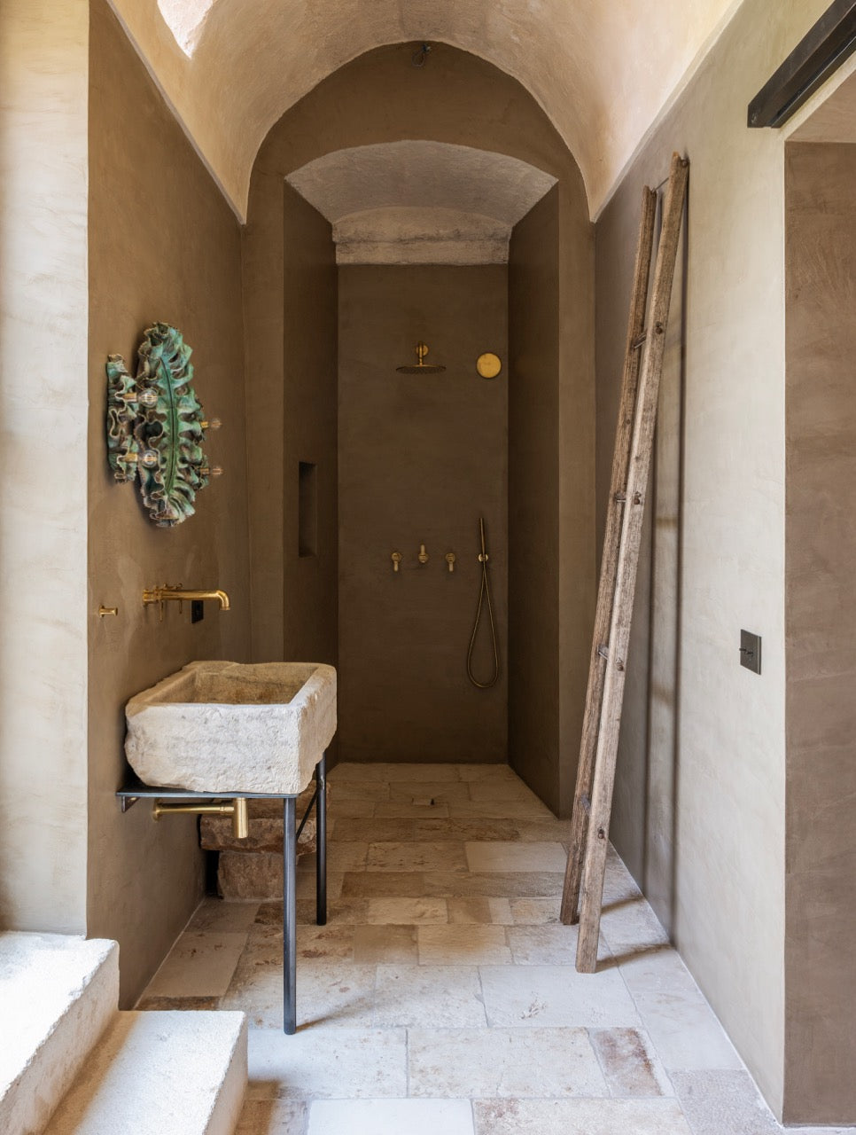 Vaulted shower room with carved stone sink and brass fittings