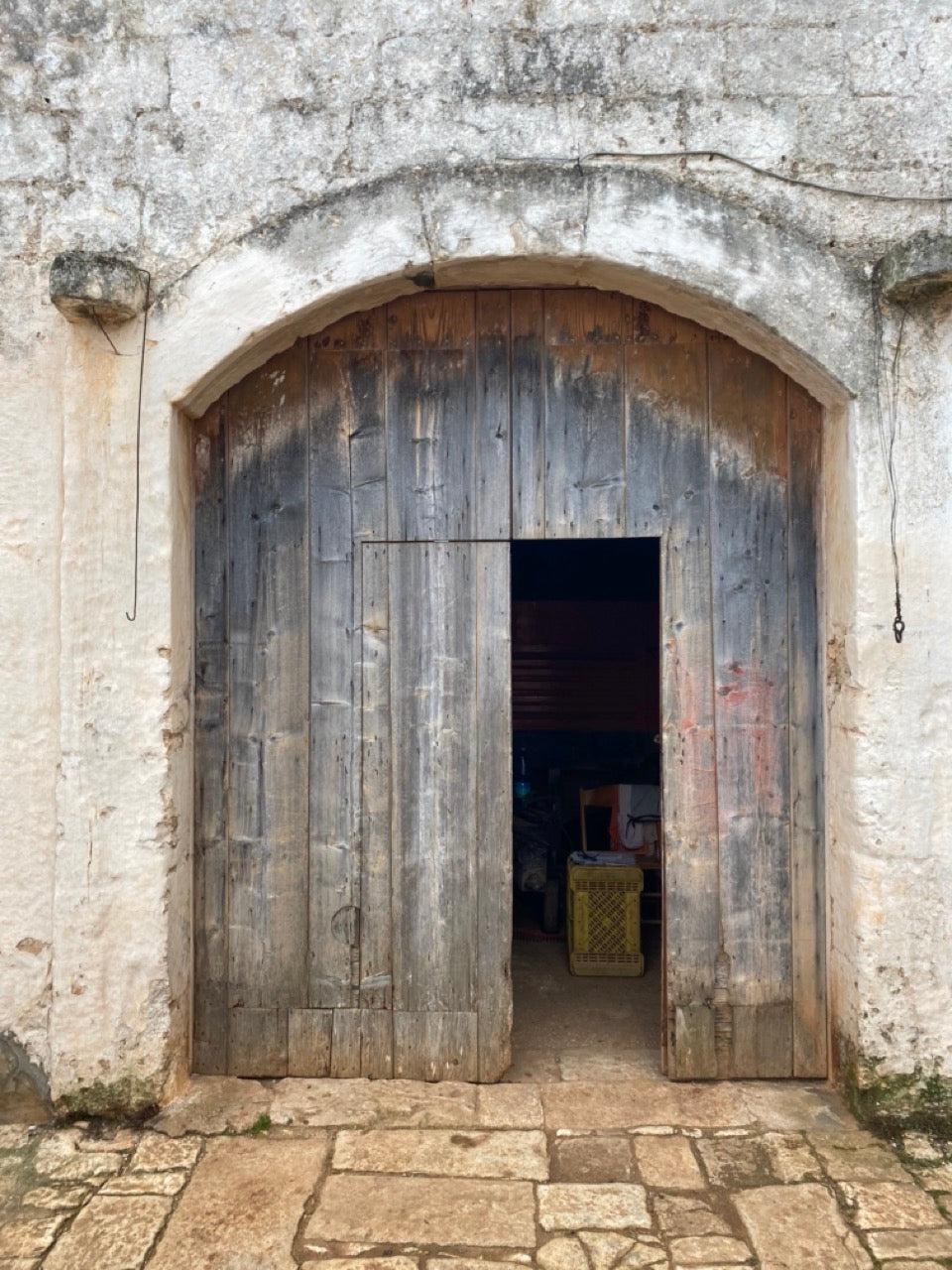 Weathered wooden arched door in stone facade before restoration