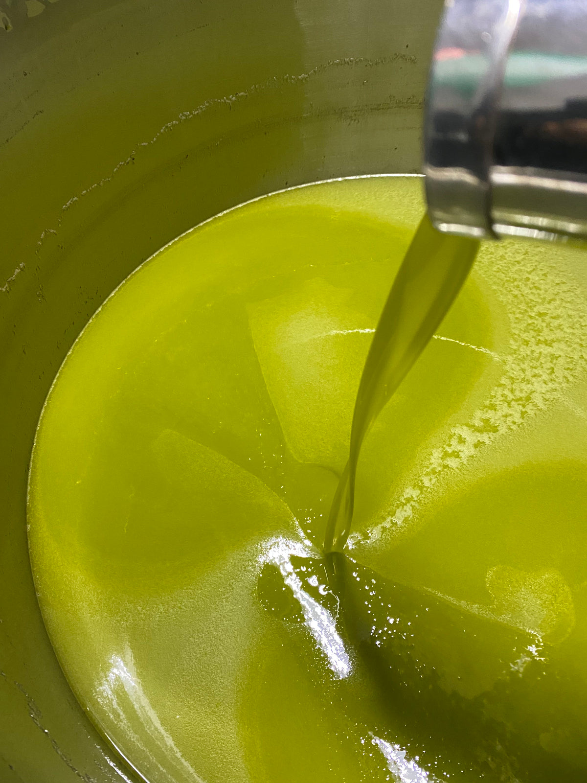 Fresh filtered extra virgin olive oil pouring into stainless steel vat