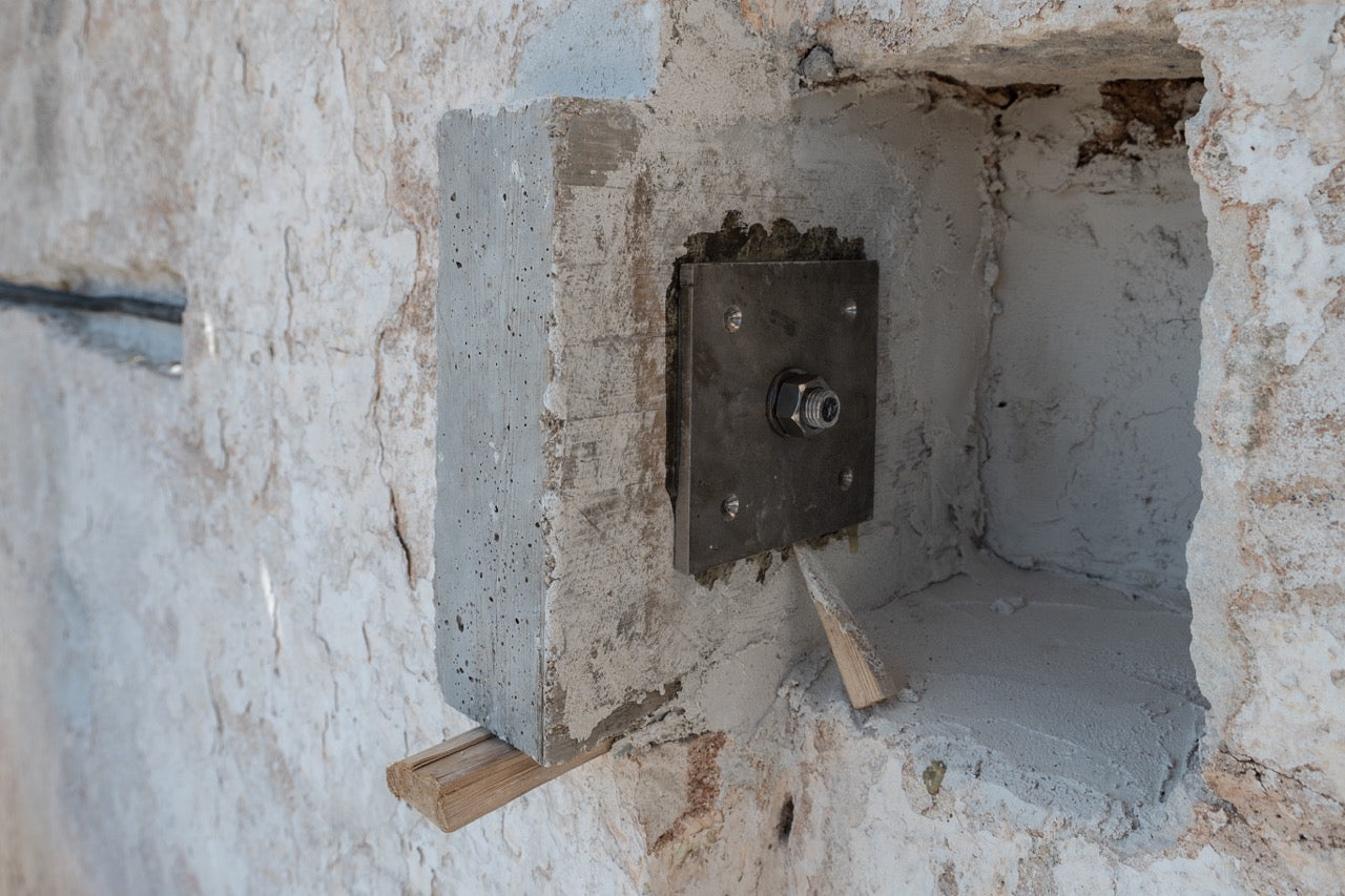 Structural reinforcement bracket embedded in stone wall recess