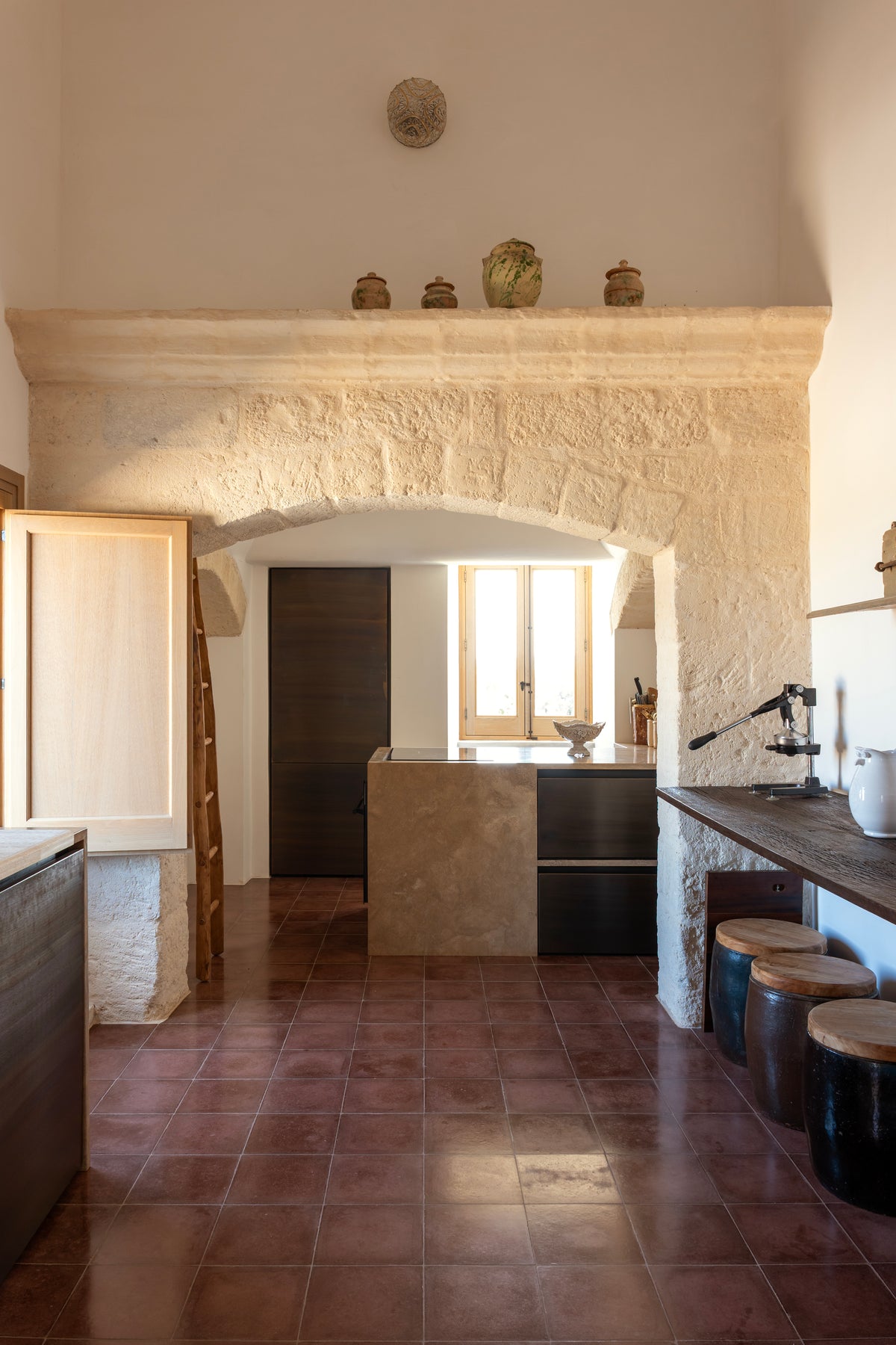 Stone archway leading to kitchen with terracotta tile floor