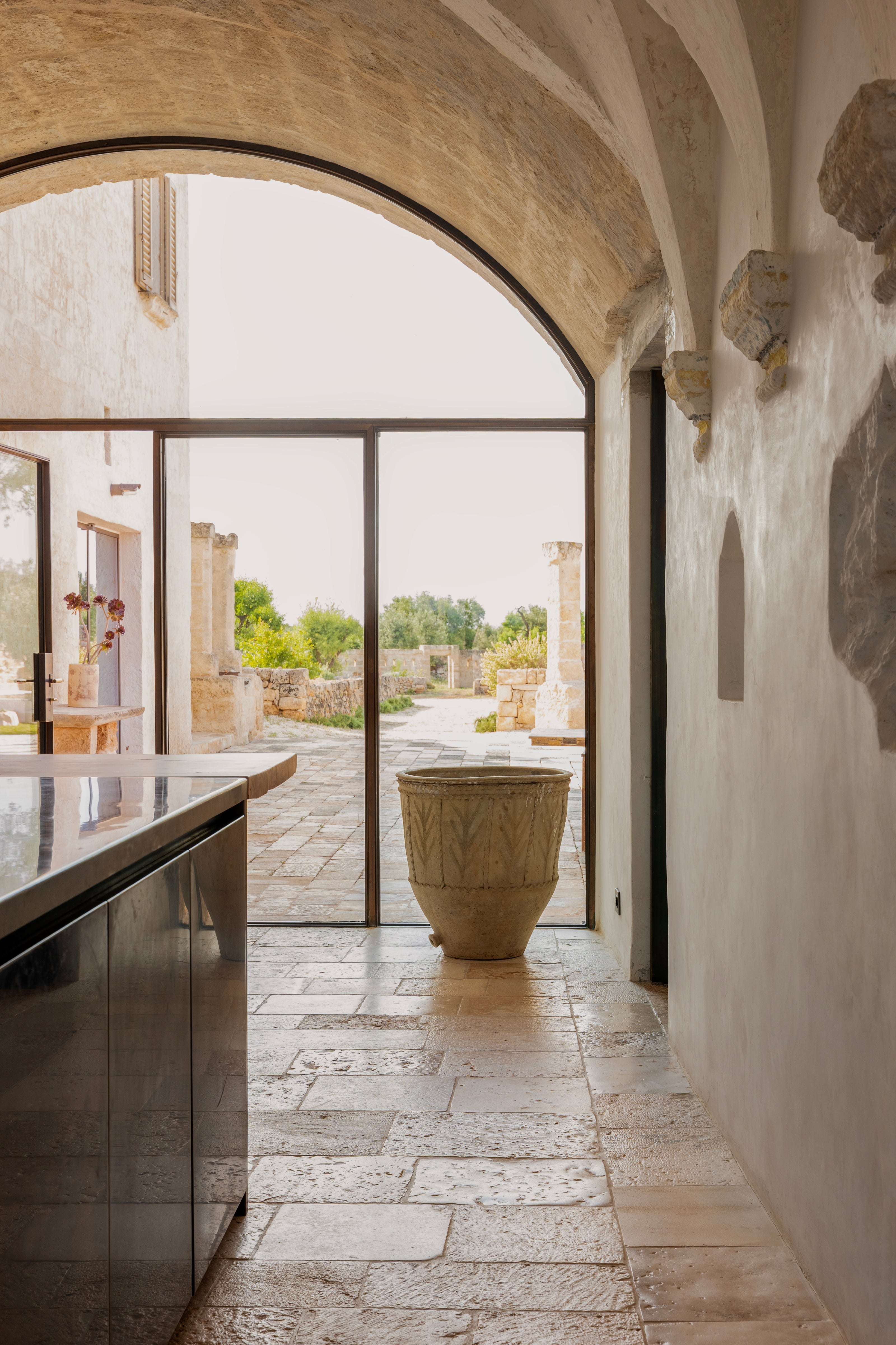 Kitchen archway leading to outdoor courtyard with terracotta urn