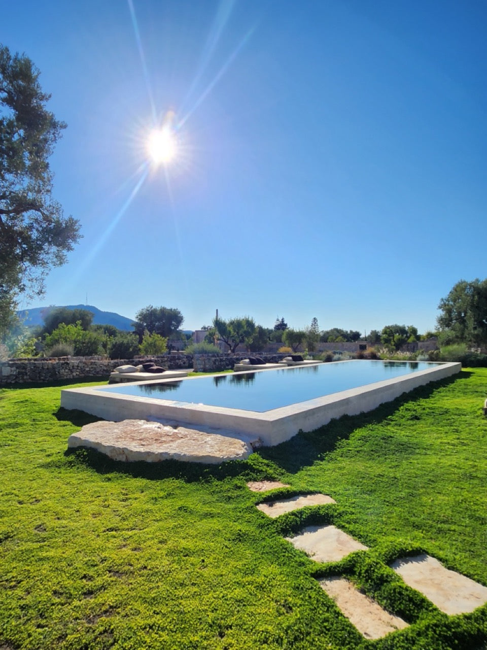 Infinity pool surrounded by lush lawn and stepping stones in Puglia