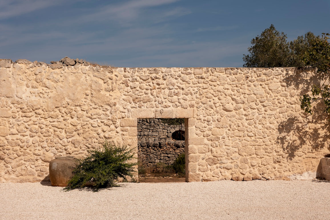 Traditional stone wall with arched doorway leading to stable