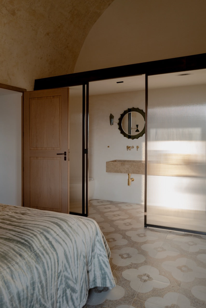 Bedroom with view into ensuite bathroom with stone sink