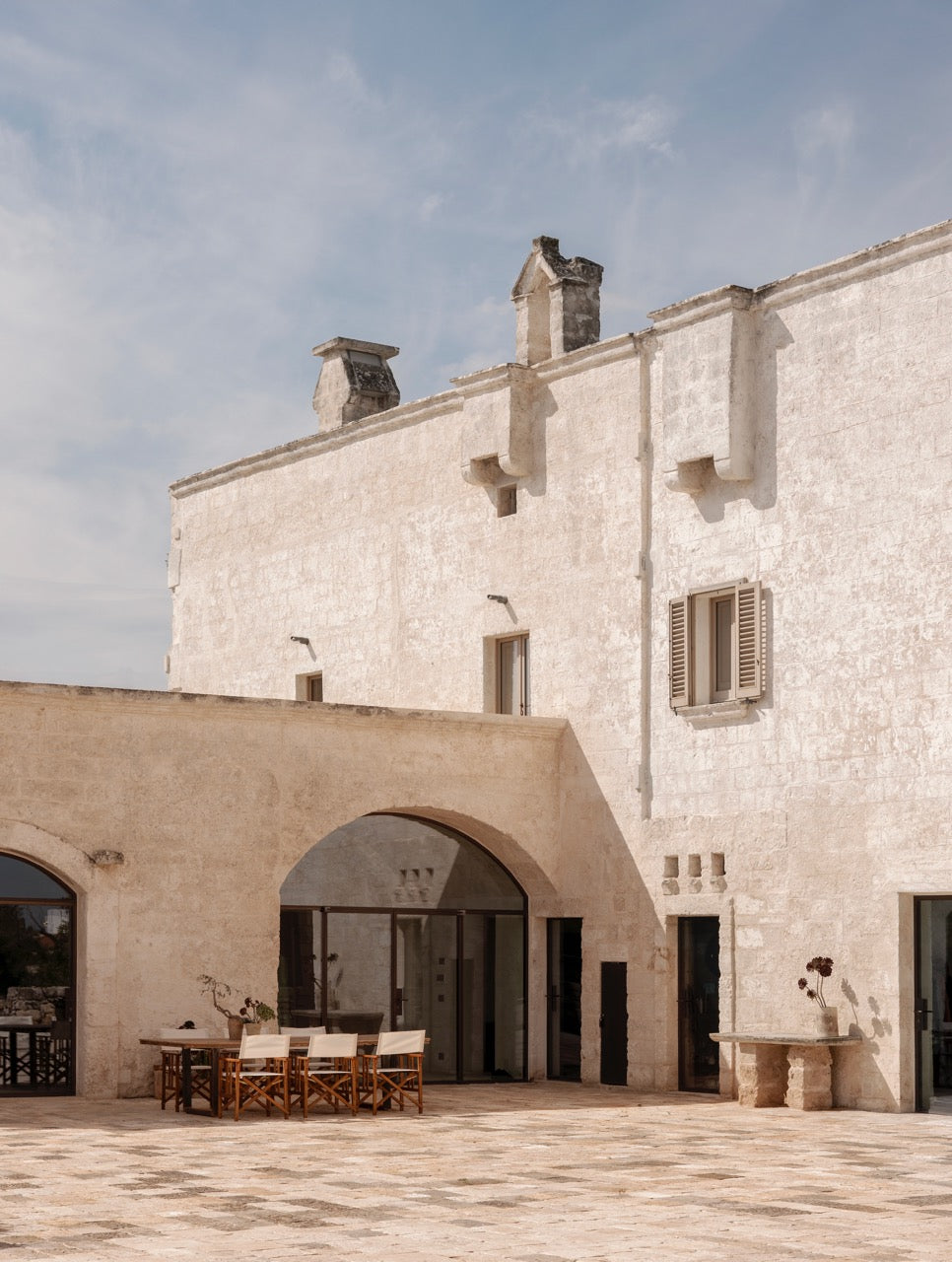Wide view of stone courtyard archway with dining area and chimneys