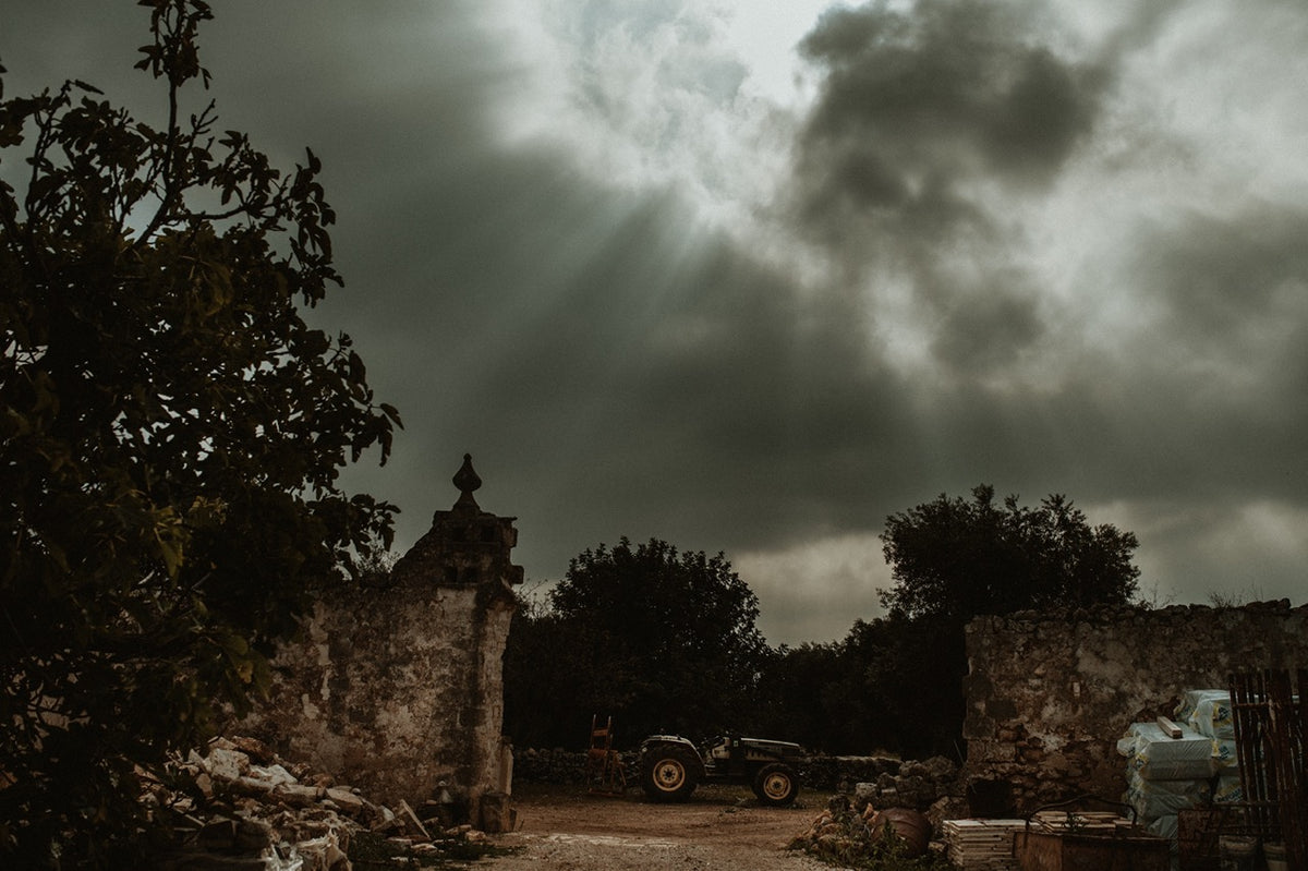 Stone ruins with tractor under dramatic sky and sunbeams
