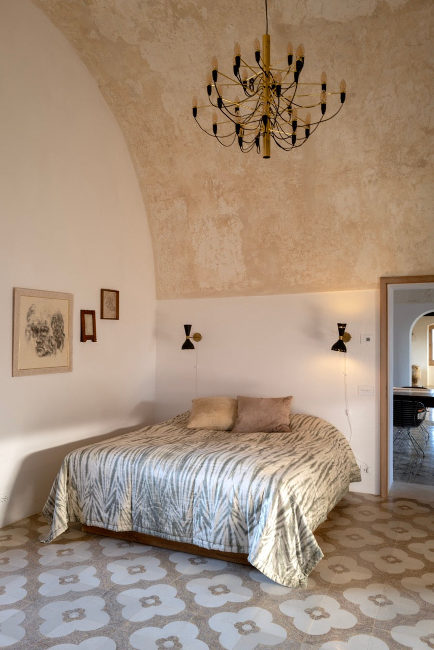 Bedroom with vaulted ceiling and vintage chandelier over patterned floor