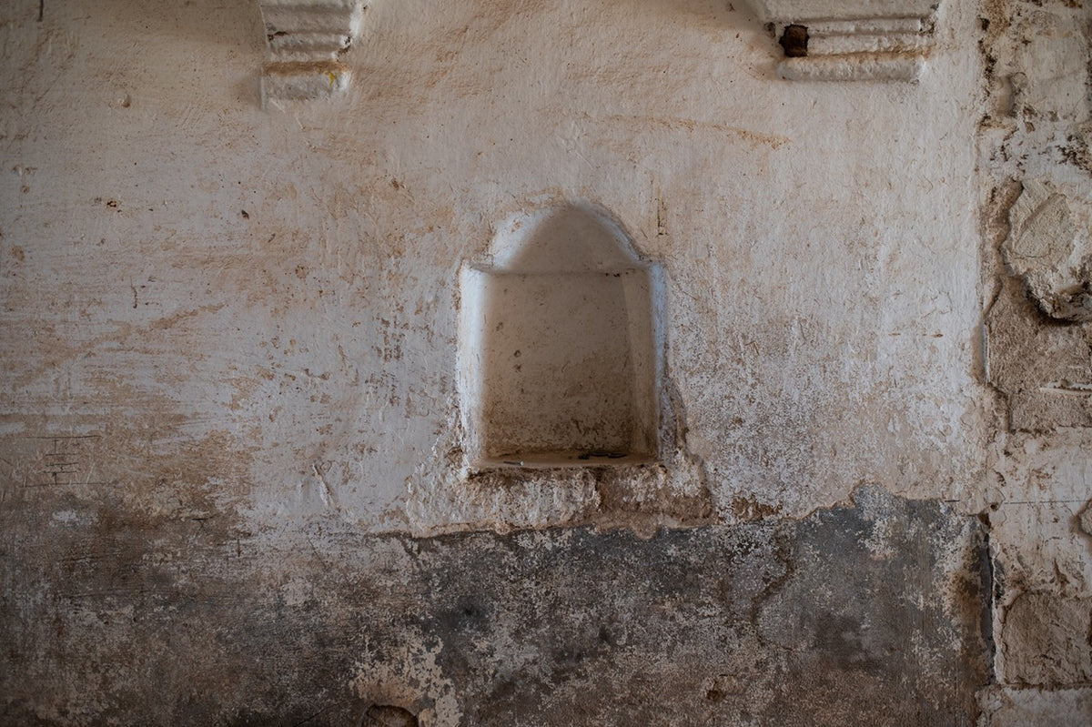 Arched stone niche carved into weathered kitchen wall