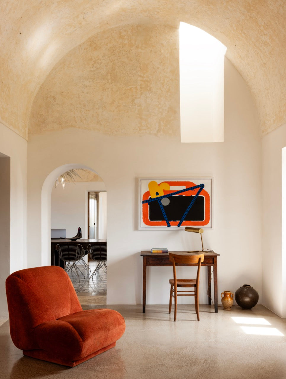 Vaulted lounge with rust armchair and antique writing desk nook