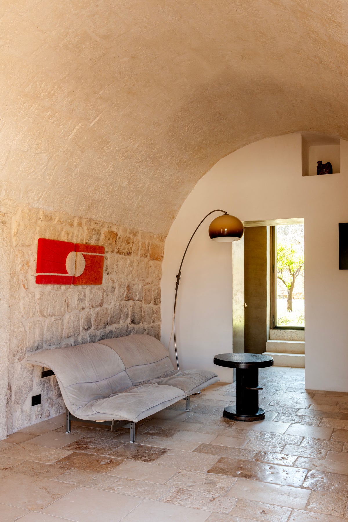 Vaulted stone lounge with grey sculptural sofa and floor lamp