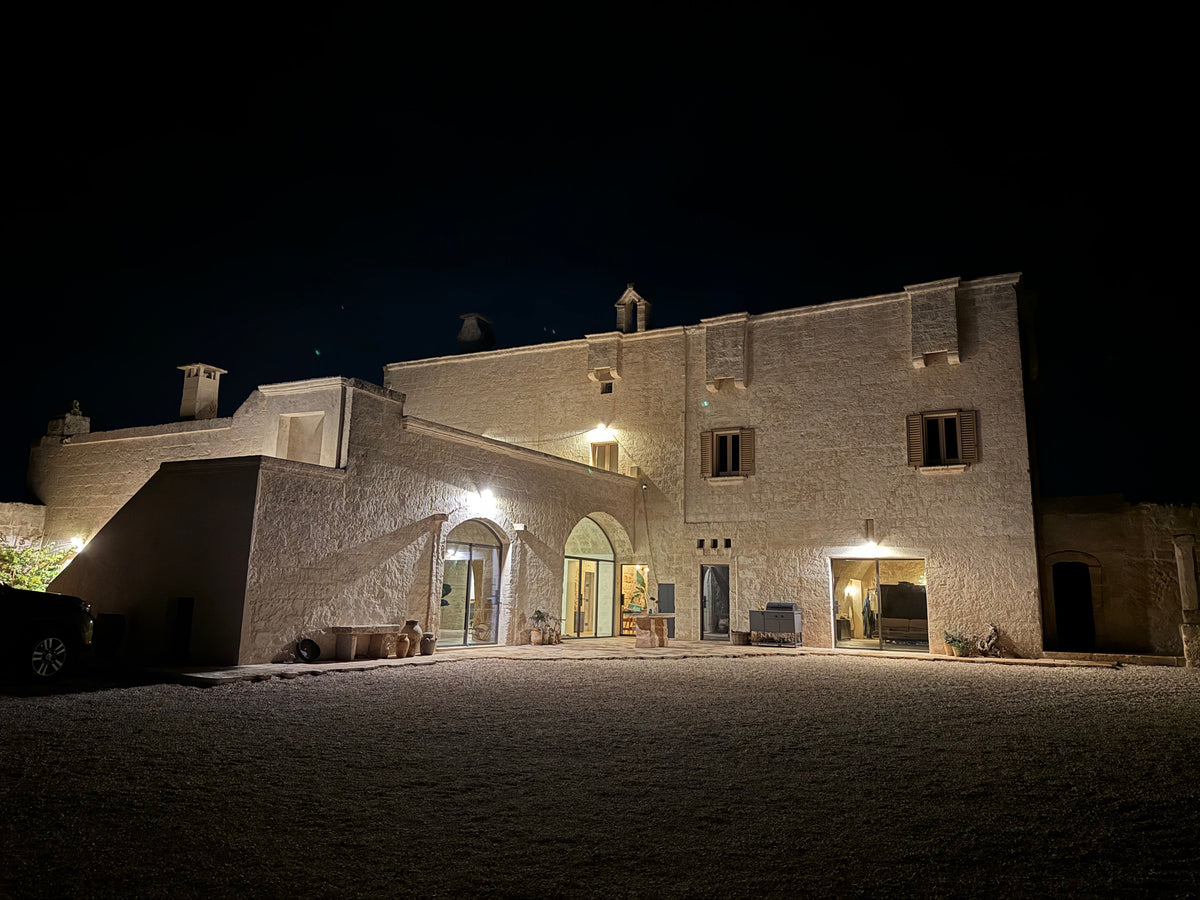 Masseria courtyard facade at night with arched doorways lit up
