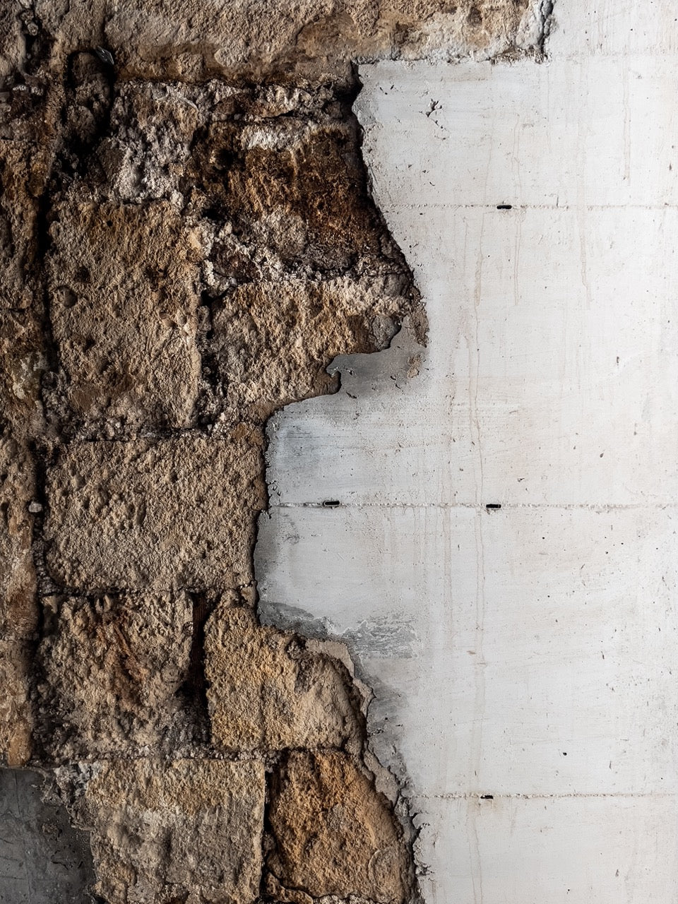 Close-up of raw stone wall meeting smooth white concrete render