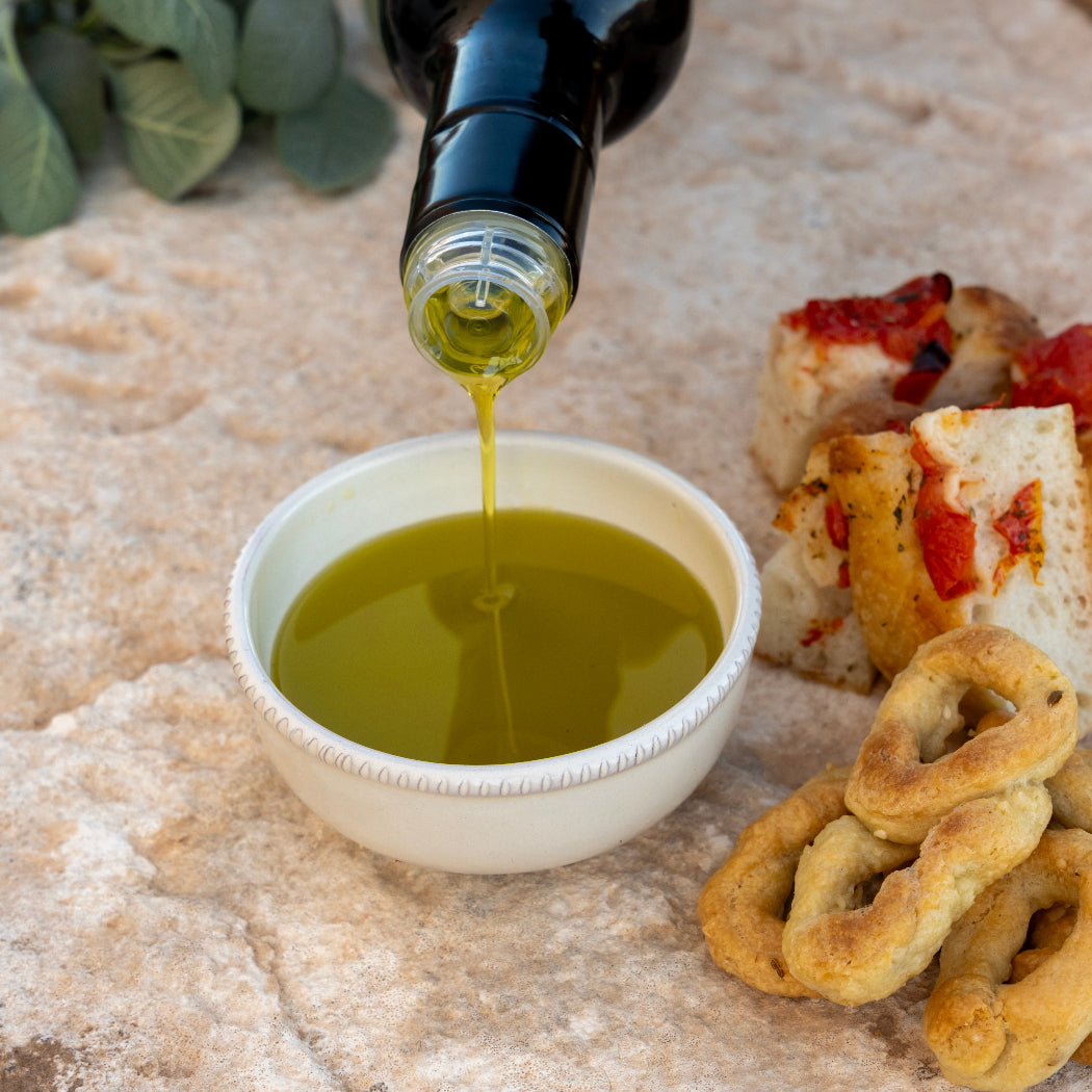 Extra virgin olive oil poured into bowl with bread and taralli