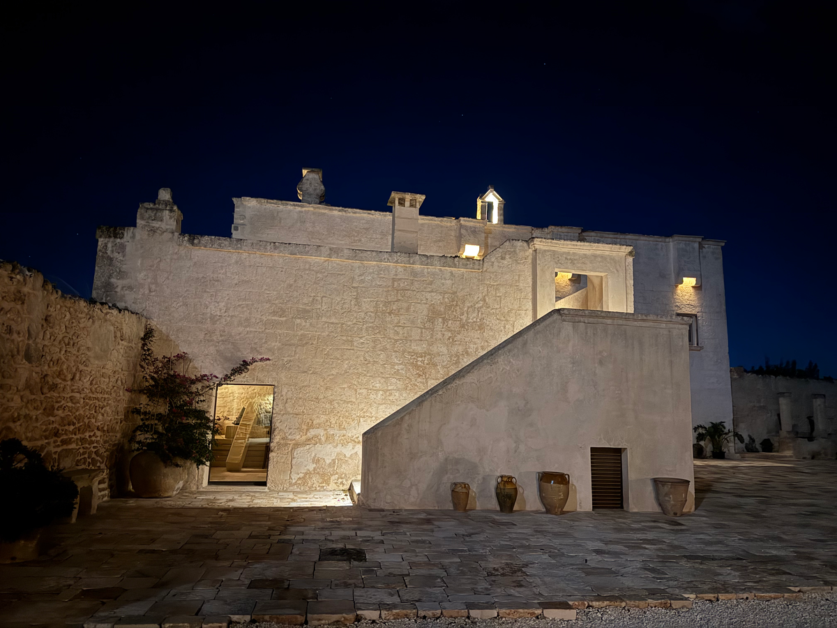 Masseria courtyard at night with outdoor staircase and terracotta urns