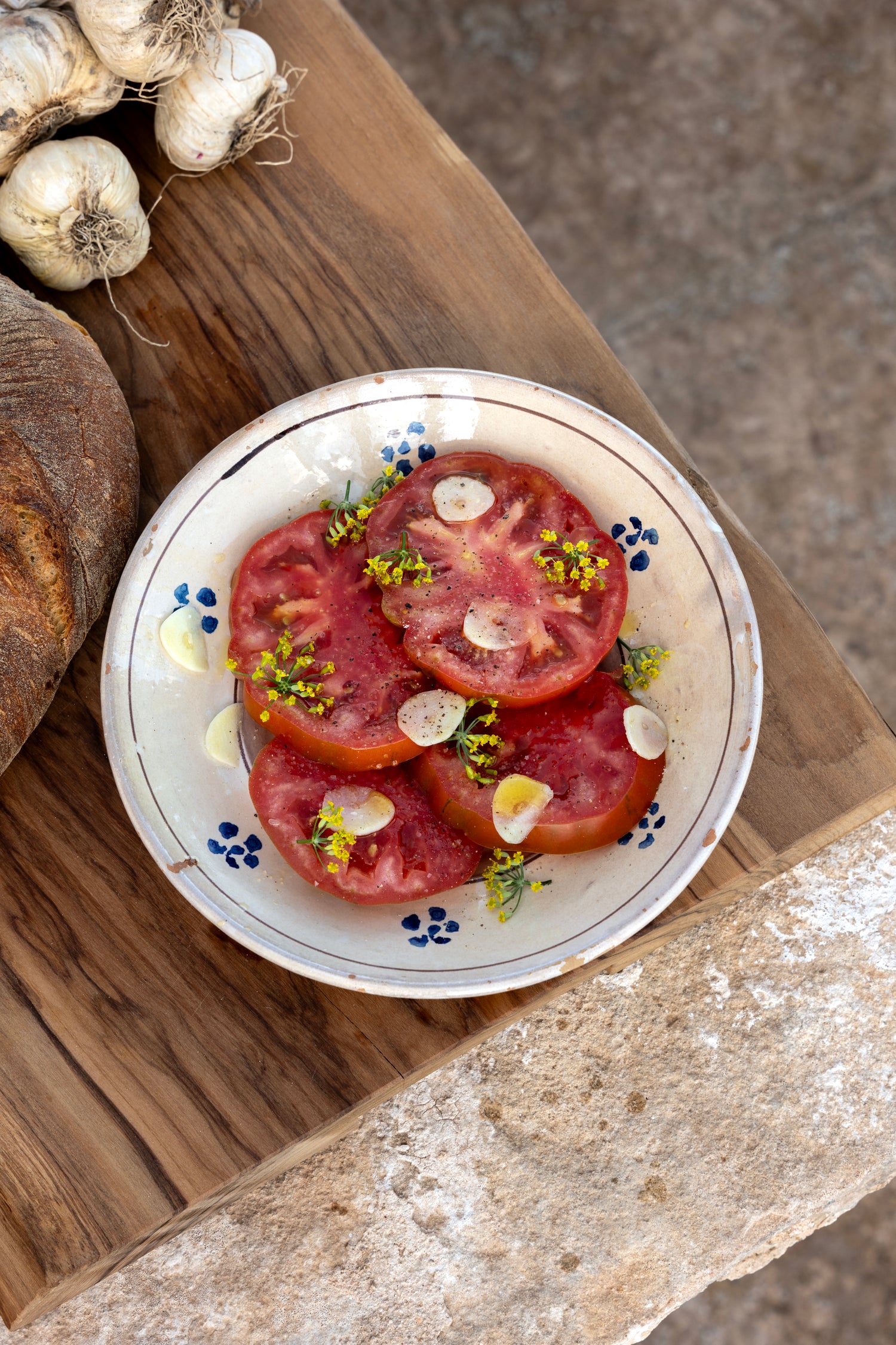 Sliced tomatoes with garlic and edible herb flowers on plate