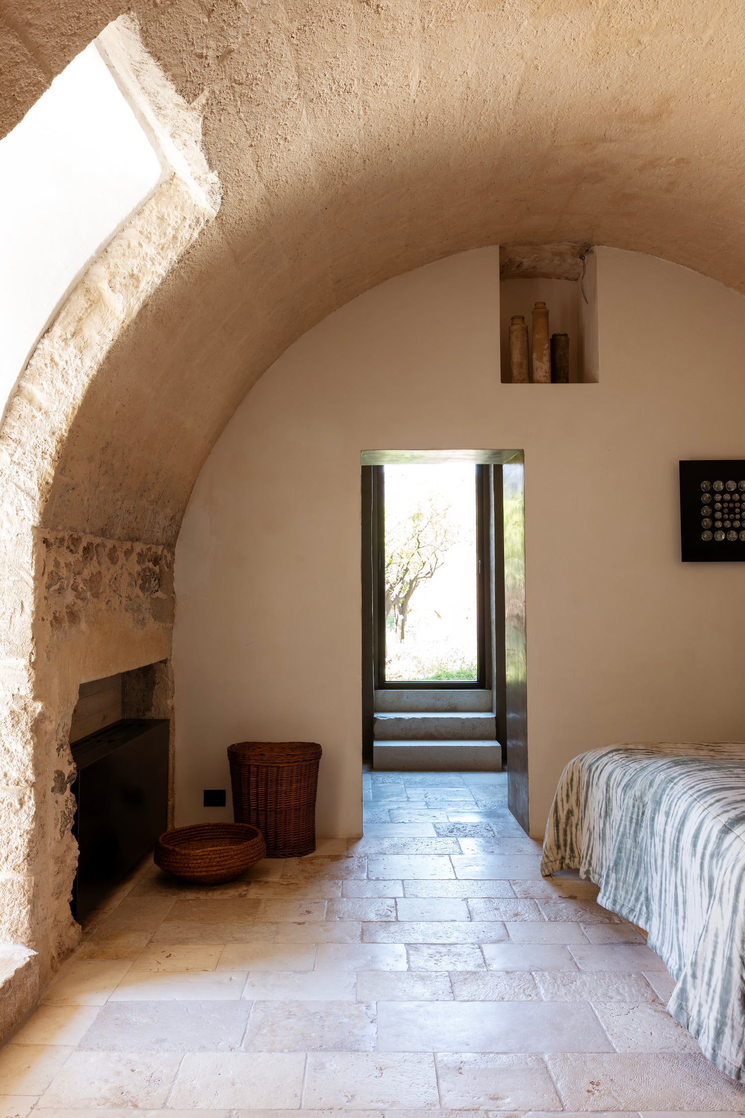 Vaulted stone bedroom with wall alcove and door opening to garden