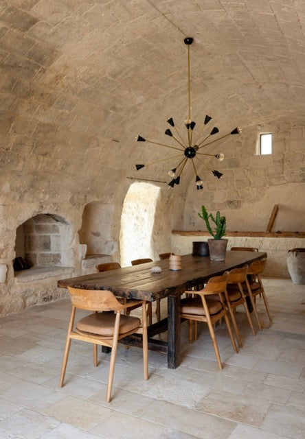 Vaulted stone dining room with long wooden table and sputnik chandelier