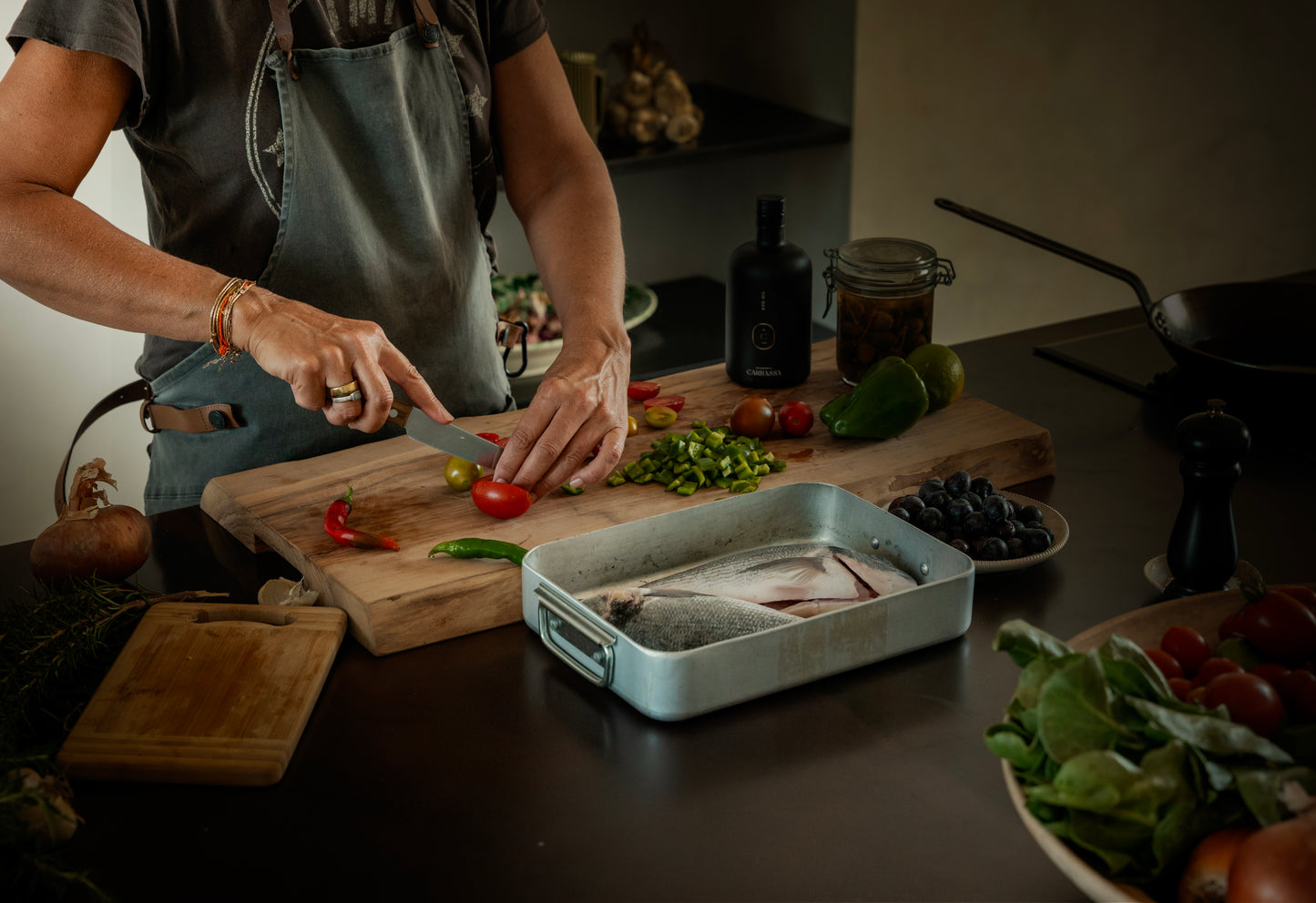 Chopping vegetables beside whole fish and Masseria Carrassa olive oil